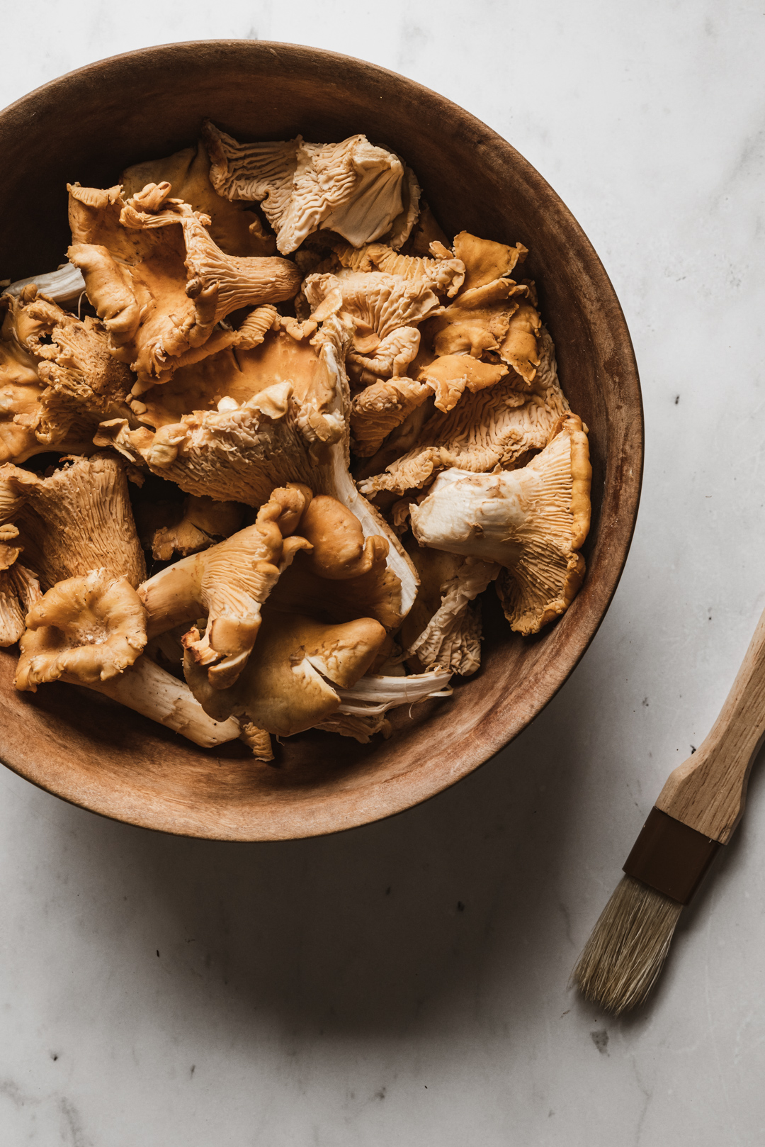 Hands cleaning chanterelle mushroom with pastry brush