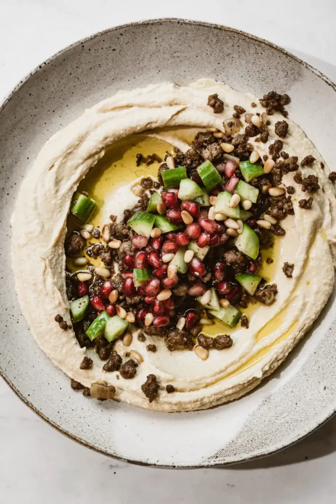Topped off with a refreshing chopped cucumber and pomegranate salad, we could eat this hummus with vegan spiced meat every day.